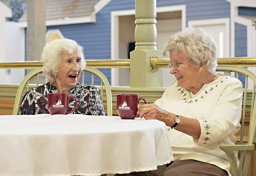 two women laughing at a patio table