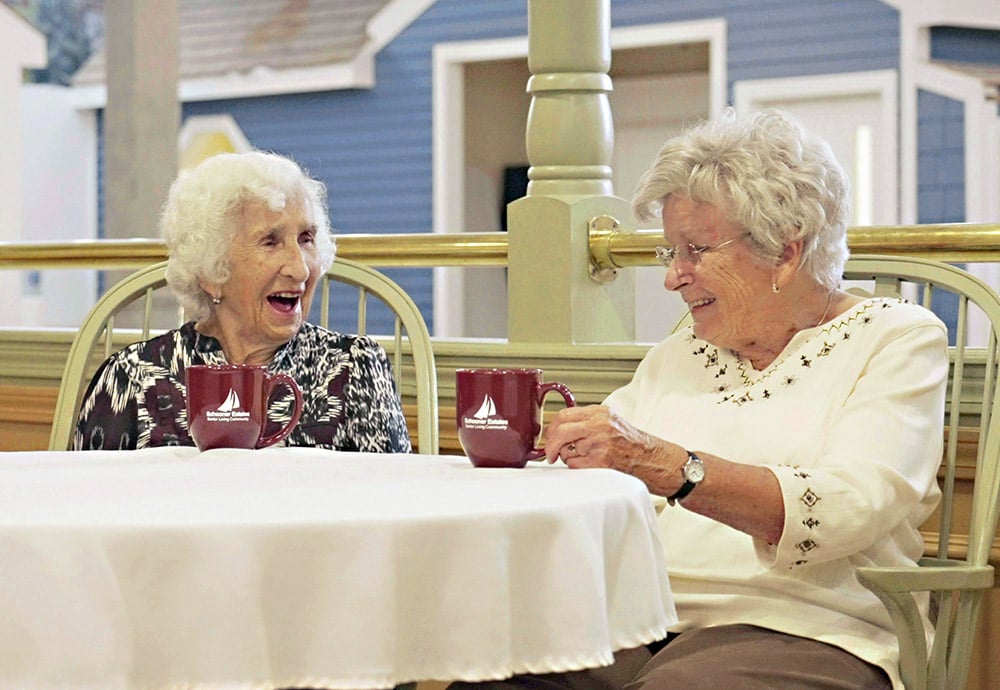 Two women laughing at a patio table