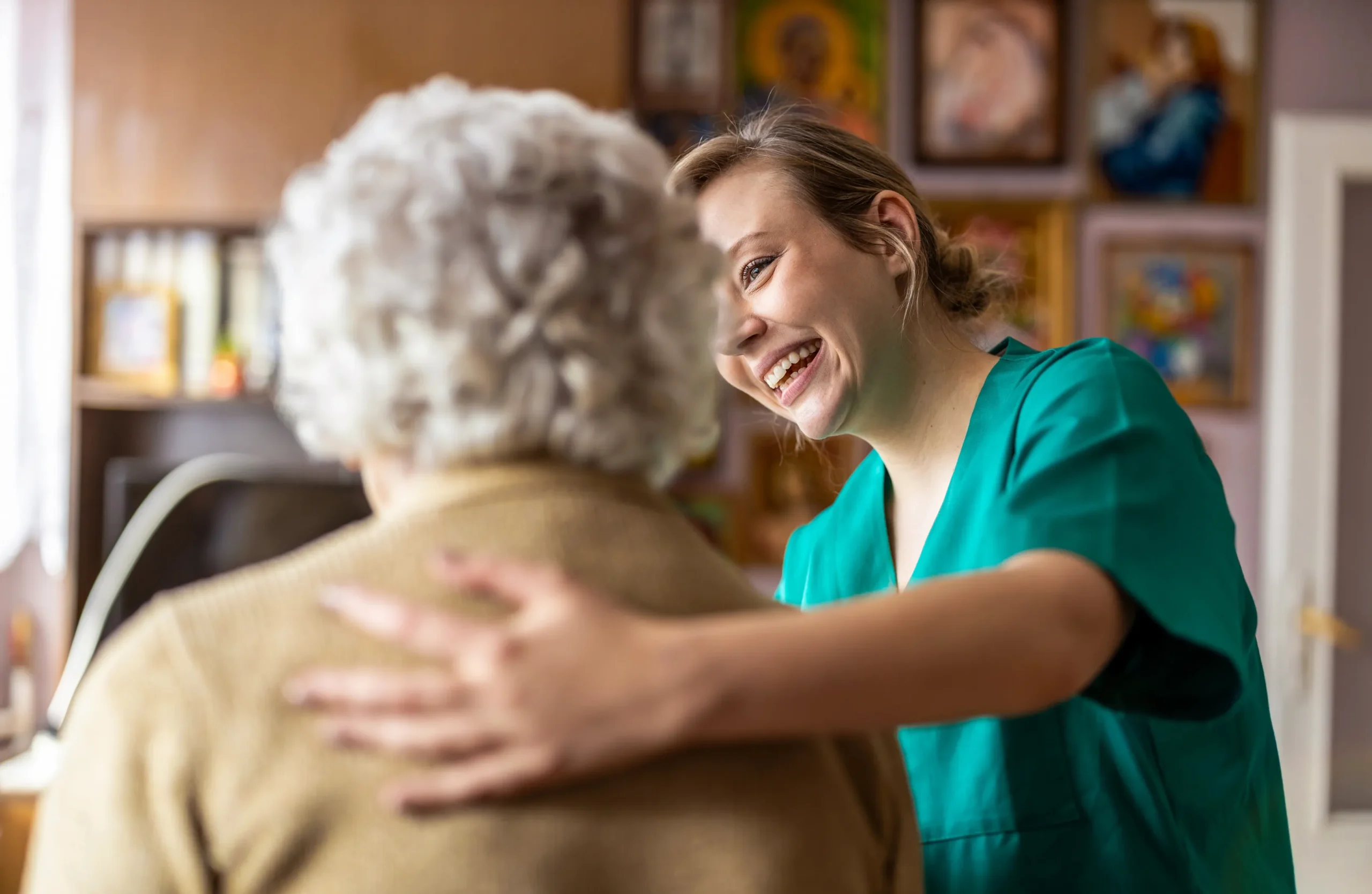 A caregiver smiling as she helps an older female resident
