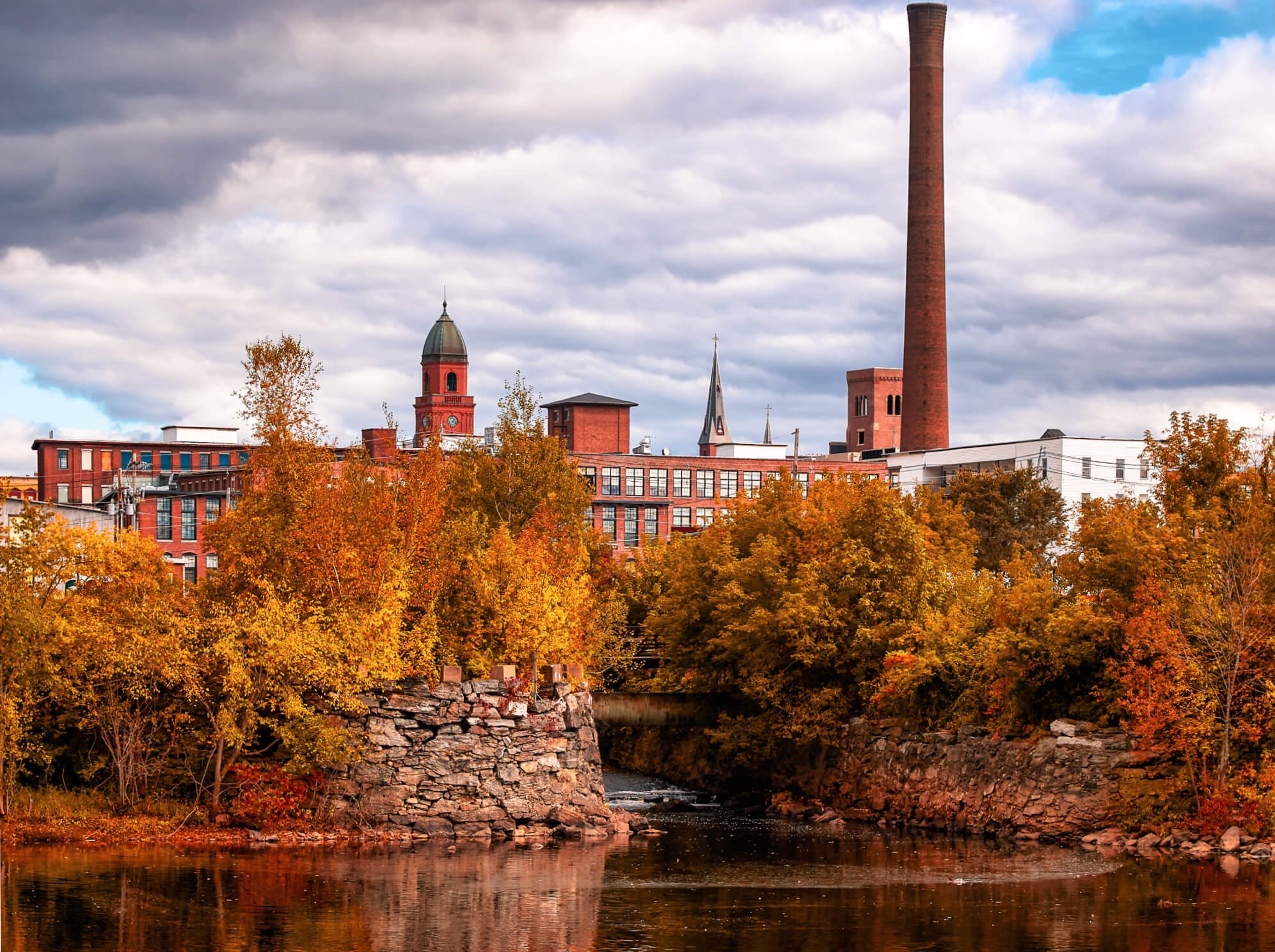 View of the mill along the Androscoggin River running through Lewiston and Auburn with visible fall foliage